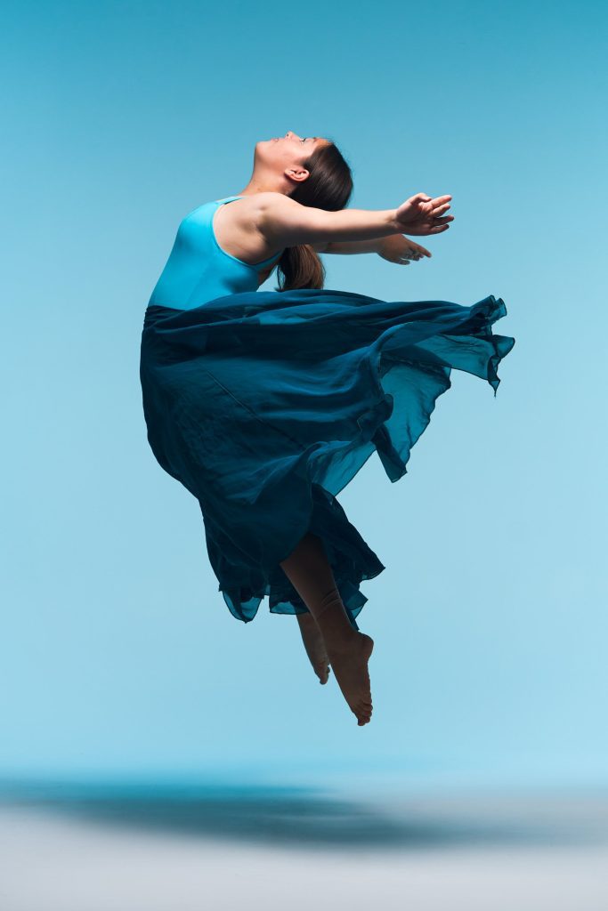 Photo of lyrical dancer doing a leap with a flowing blue skirt