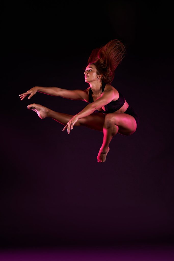 Photo of dancer doing a wolf leap looking away from camera