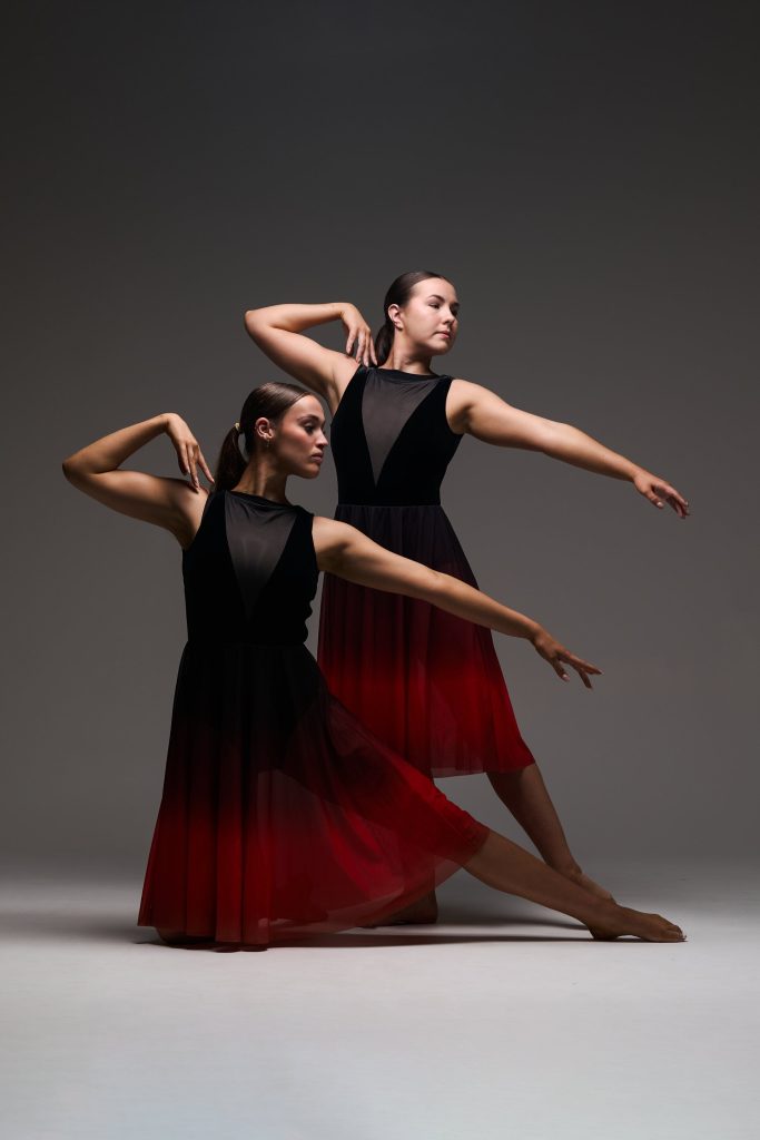 Photo of two female lyrical dancers posing in red and black skirts